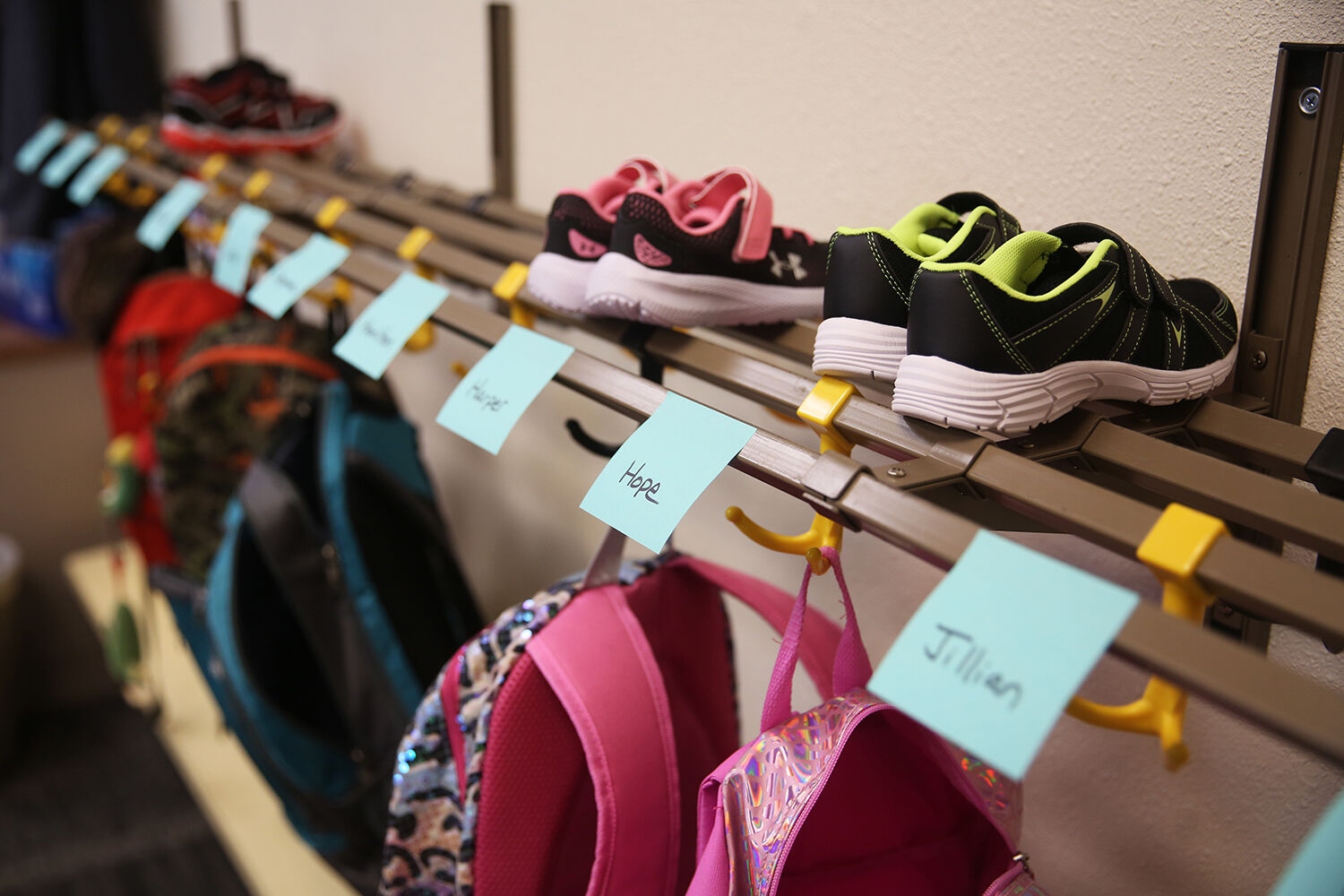 Sticky notes with each student’s name hang on the storage rack
